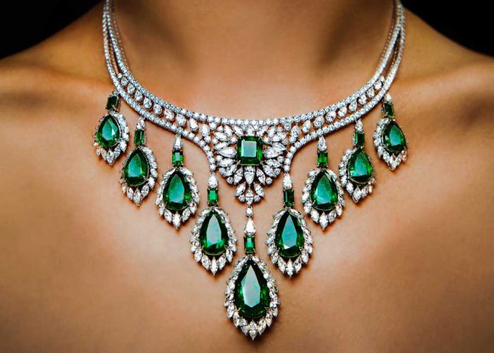Image a woman wearing a large necklace with diamonds and emeralds