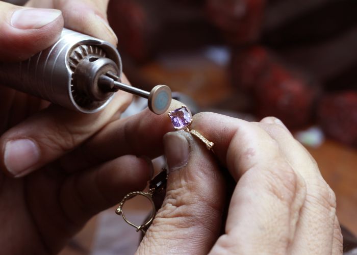 A jeweler polishes the prongs on a ring